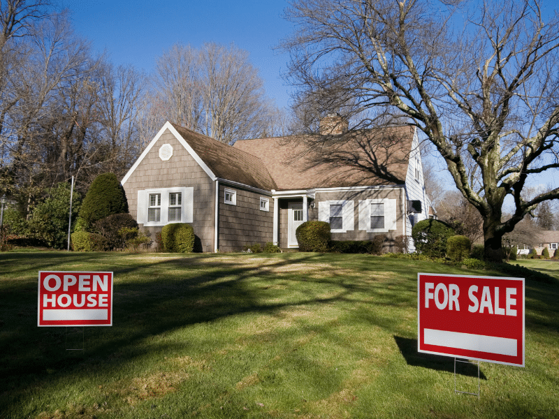 A house with a for sale sign and a open house sign in the front.