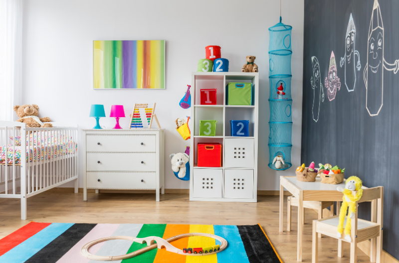 Kids bedroom with toys and stuffed animals spread across the room on shelves and a small wooden table.
