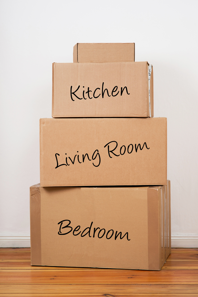 Boxes labeled and stacked on the floor in a room.