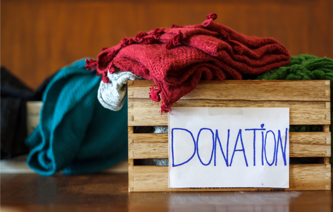 A box of blankets thats labeled with a donation sign.