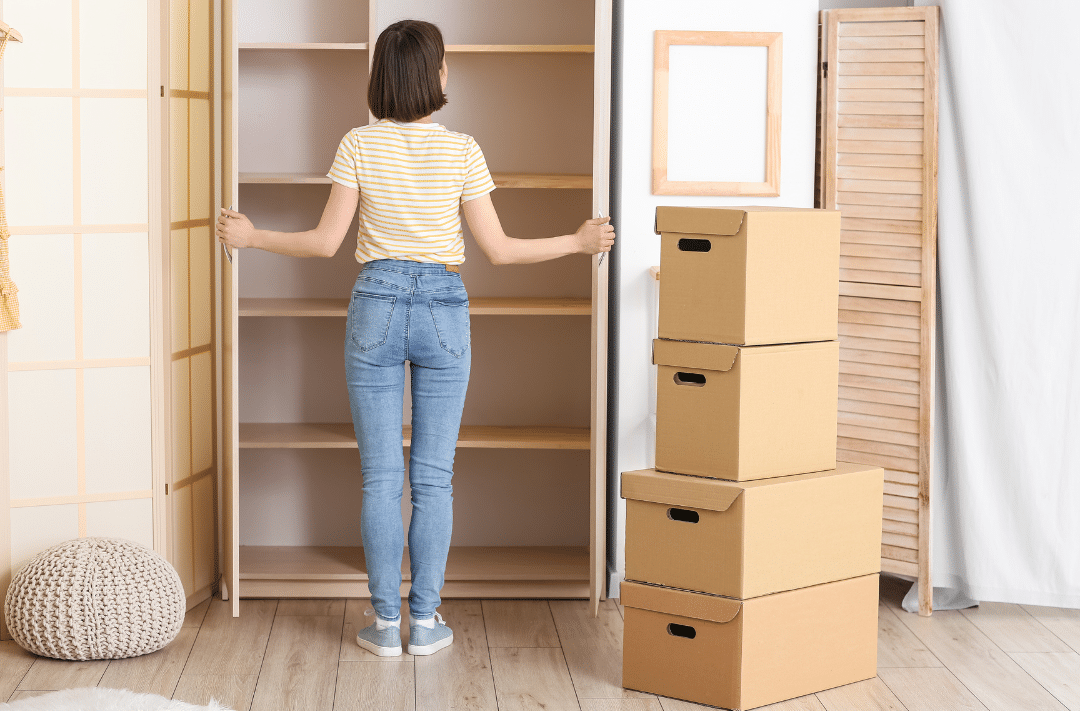 A woman looking at an empty closet after moving out.