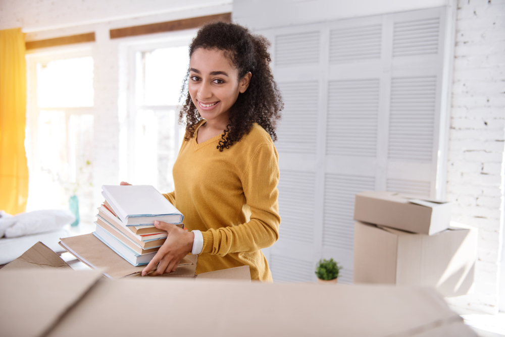 A woman packing books into a cardboard box.