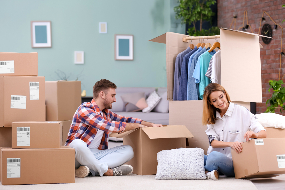 A couple unpacking boxes in the new home surrounded by boxes.