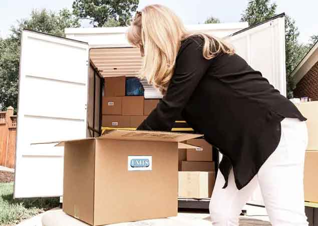 Woman packing a UNITS Moving and Portable Storage container and boxes.