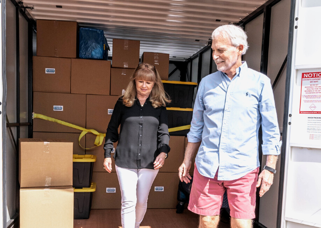 Man and woman exiting a UNITS Moving and Portable Storage Container filled with cardboard boxes and plastic containers.