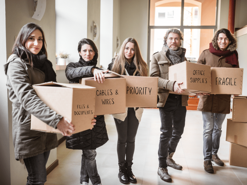 Family each carrying a cardboard box. Each box labeled differently.