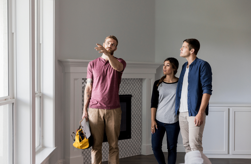 A couple listening to a contractor talk to them about their house.