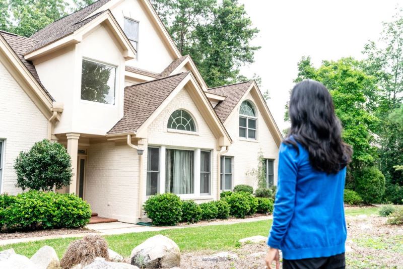 A woman standing in front of a house.