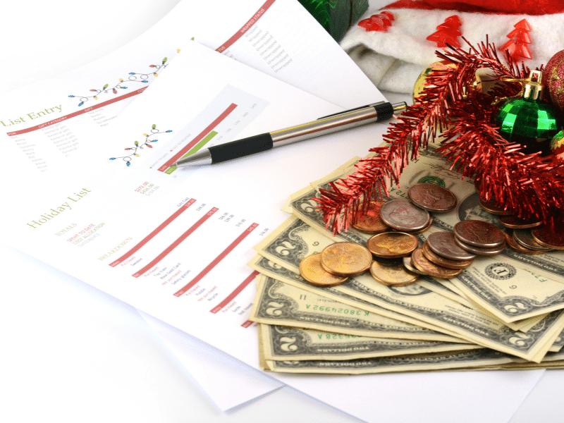 A holiday shopping list with money and coins on top of it.