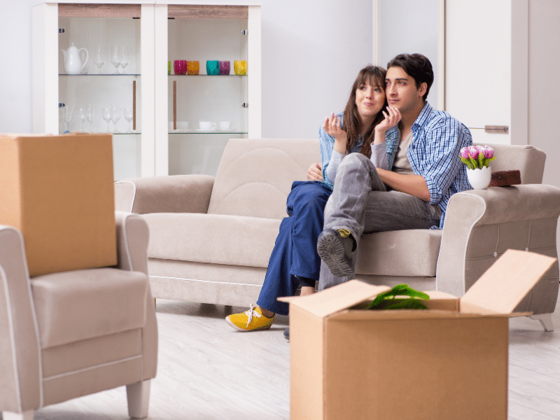 Couple cuddling on a couch in their new apartment.