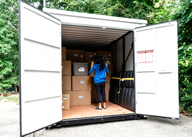 A woman standing inside of a container packed with boxes.