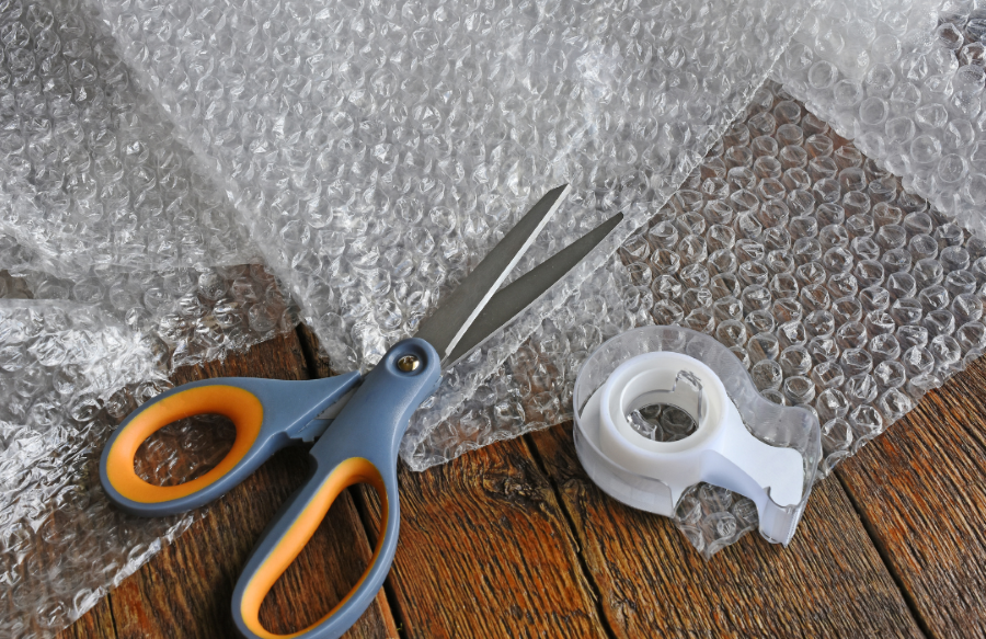 Bubble wrap with scissors and tape laying on top of it.