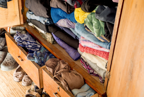 Clothes and blankets stacked and organized in a dresser.