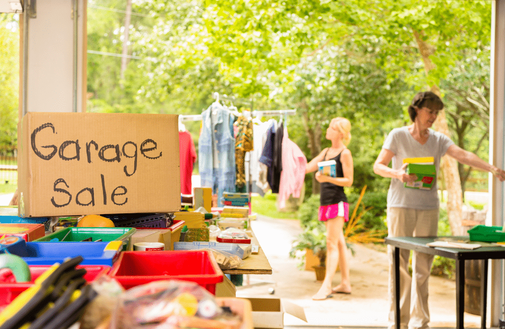 Two people looking around a garage sale with a garage sale sign.