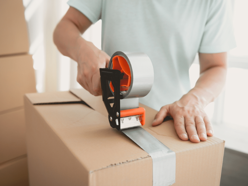 Man taping a cardboard box closed.