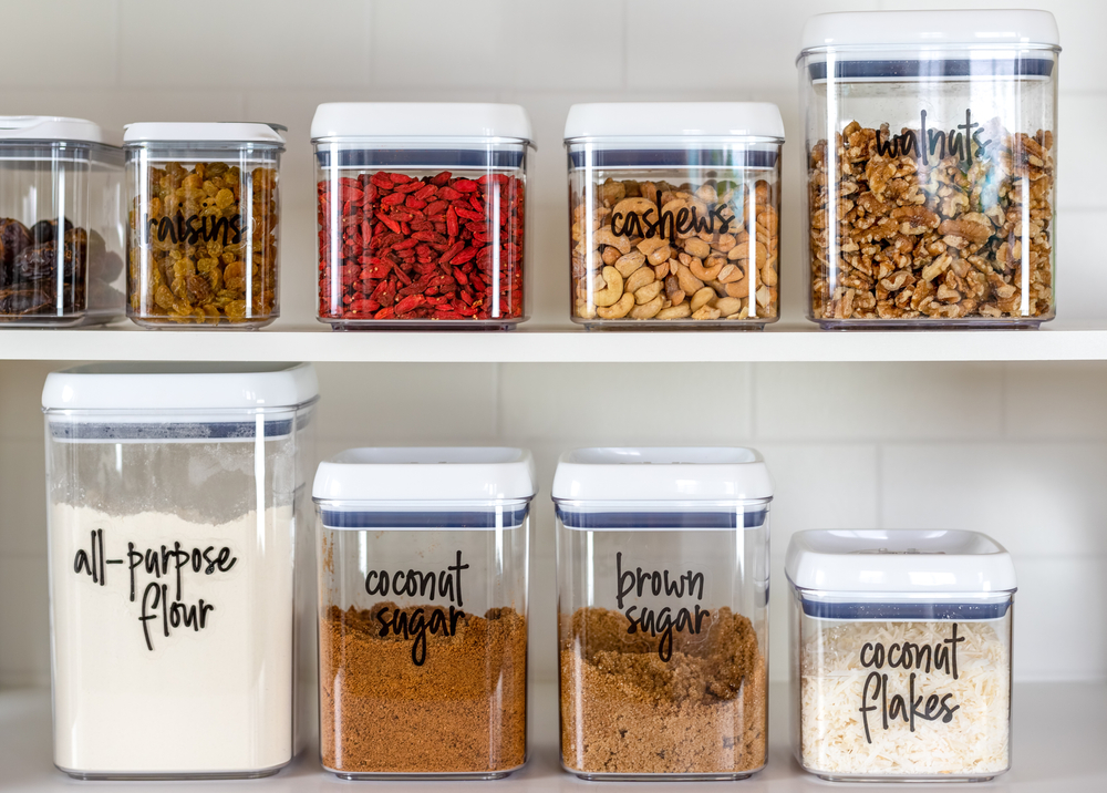 Pantry shelf with jars and containers filled with nuts and various spcies.