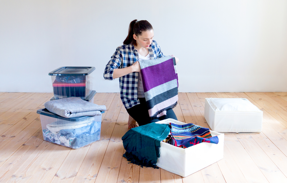 Woman packing blankets into plastic storage bins.