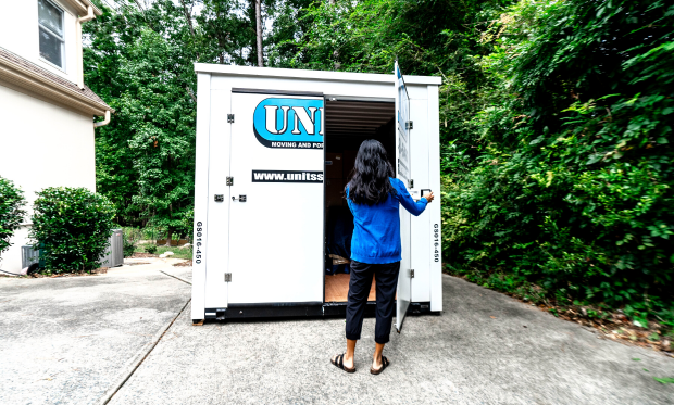A woman standing and opening the door of a Units of North Shore container.