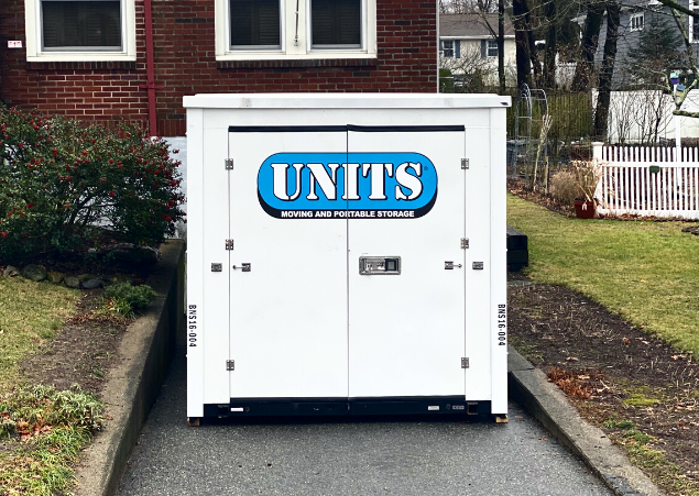 A Units of North Shore container sitting in the driveway of a house.