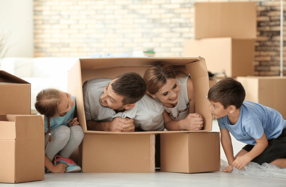 A family playing with their children using cardboard boxes.