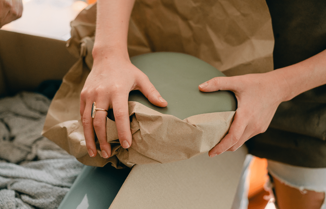 A person packing items with brown paper.