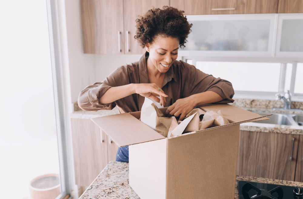 A woman unpacking items from a box into a new house.