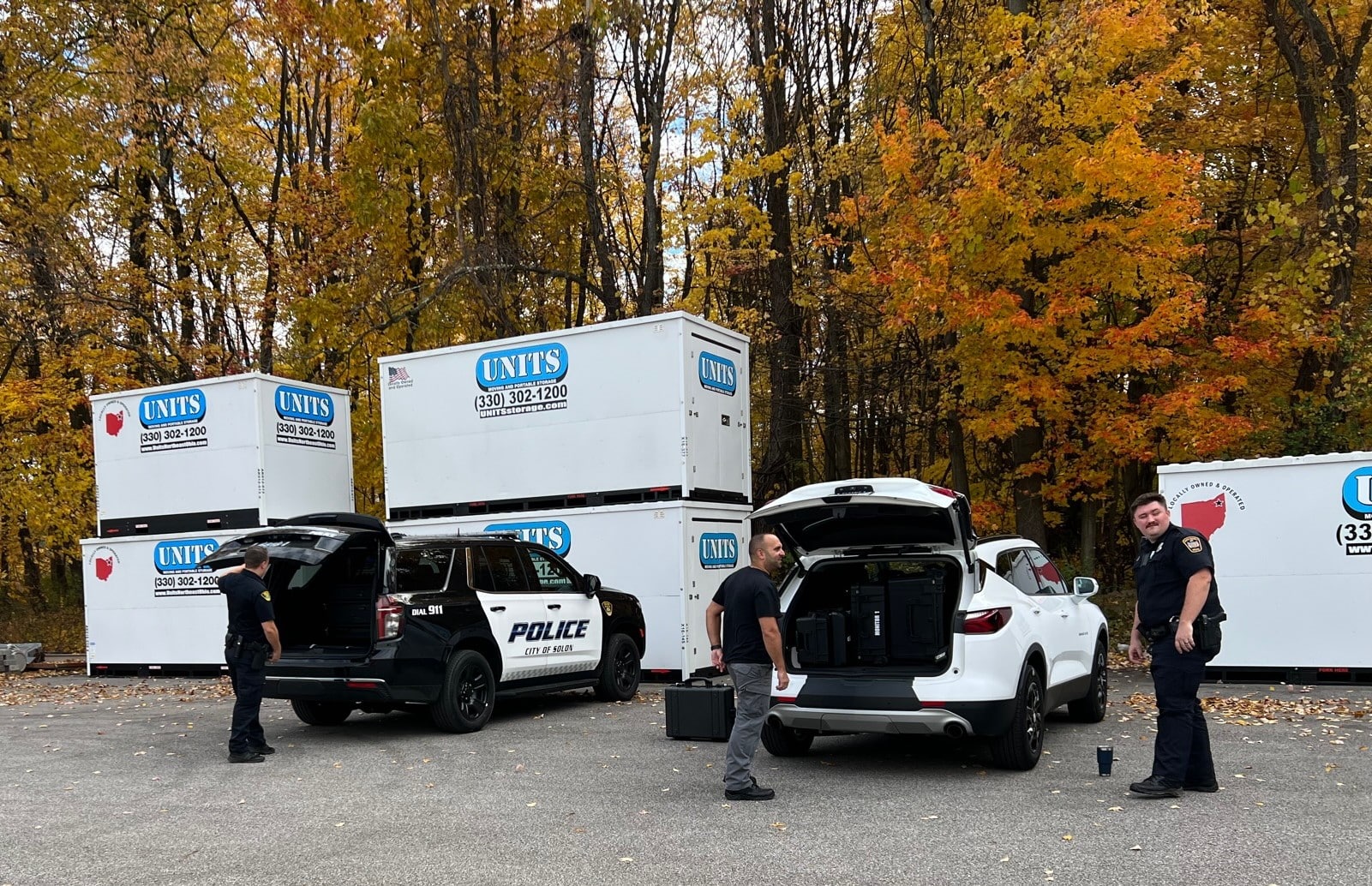 Three police officers standing in front of Units Of Northeast Ohio containers.