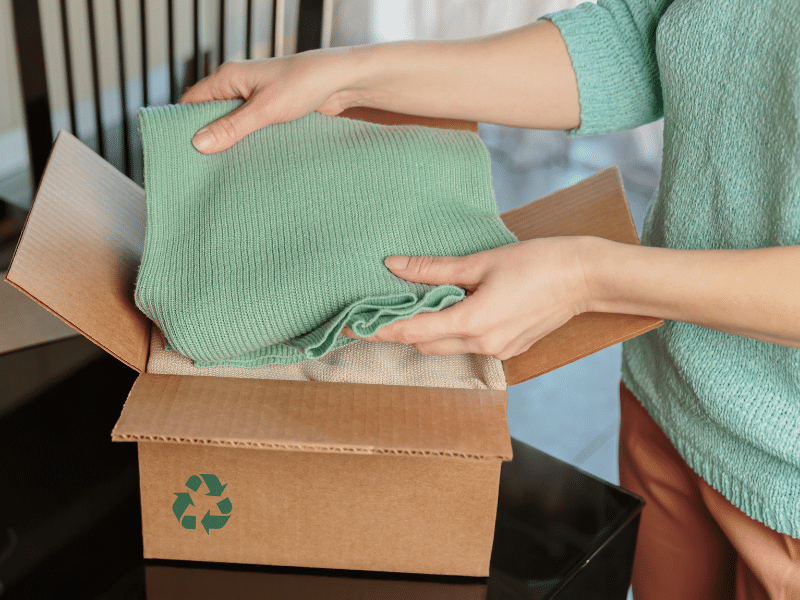 A person packing blankets into a cardboard box.