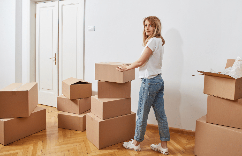 A woman standing in a room surrounded by boxes.