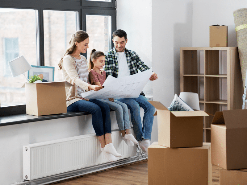 A family looking at floor plans for a house surrounded by boxes.