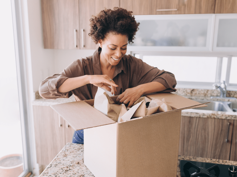 A woman unpacking items from a box into her new home.