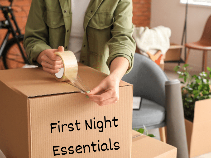 A woman packing a box with tape thats labeled first night essentials.