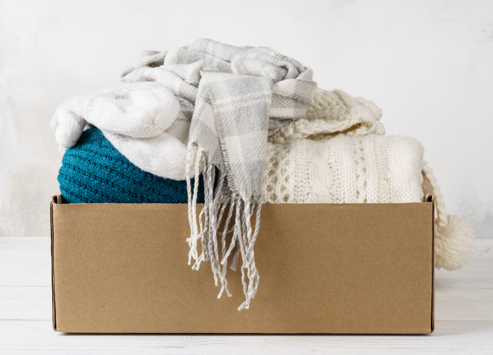 Units of Omaha & Lincoln sweaters and blankets sitting inside a box