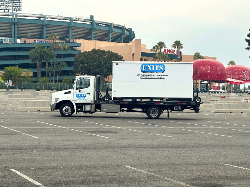 UNITS Moving and Portable Storage Container on the back of a truck in a stadium parking lot.