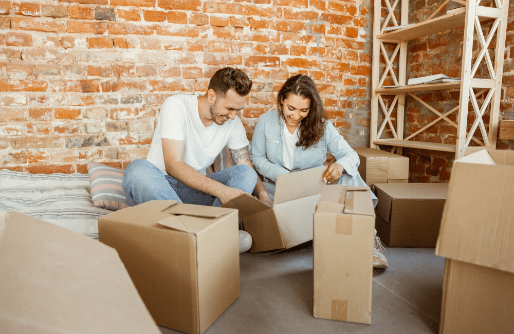 Couple going through cardboard boxes while sitting on the floor.