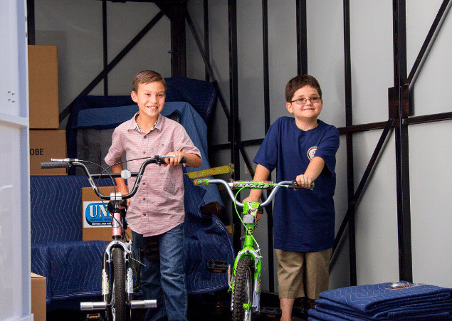 Two boys getting their bikes out of a portable storage container.