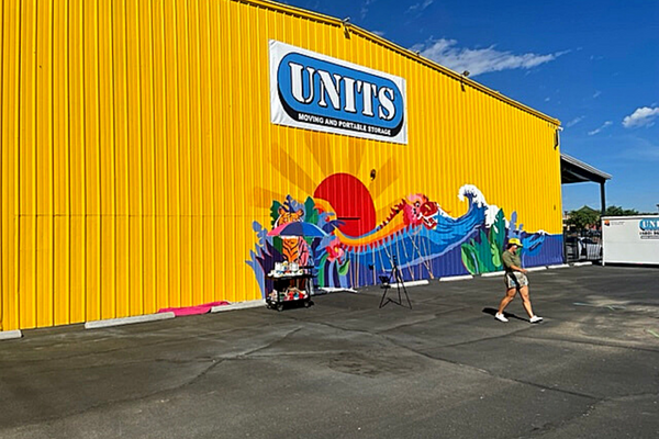 UNITS logo on a yellow building with a dragon, tiger and ocean painted on.