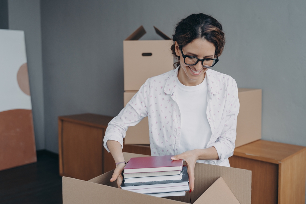 Woman with glasses packing her books away in a cardboard box.
