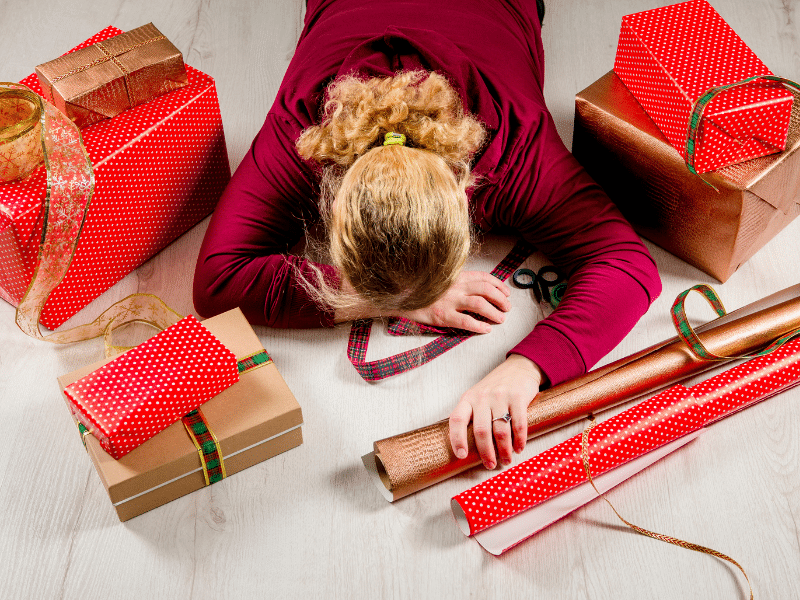 Woman lying face down with wrapped gifts around her.