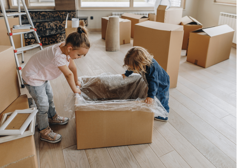 Two kids looking at an unpacked cardboard box.