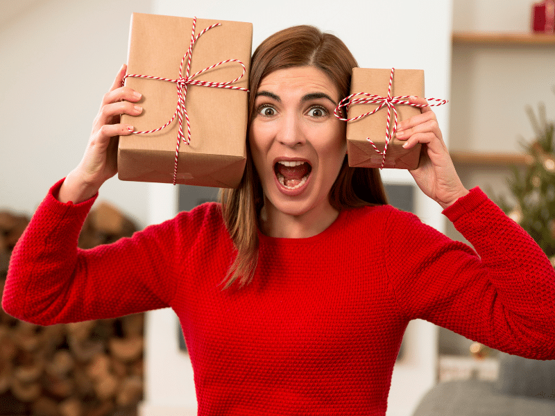 Woman screaming while holding to boxes with holiday wrapping string on them.
