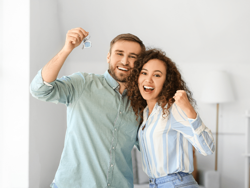 A couple smiling happy holding a pair of keys.