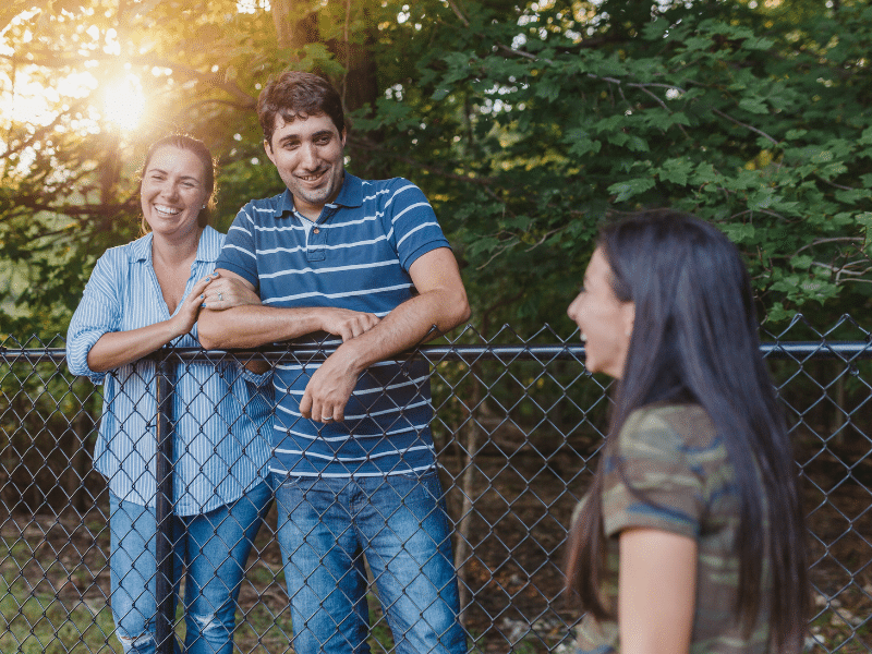 A Couple talking to a woman with a fence in between them.