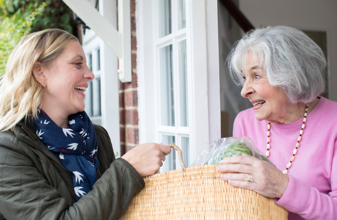 Woman handing a basket to an elderly woman.