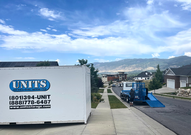 Units Of Utah container sitting in a driveway, and a truck parked in the street.