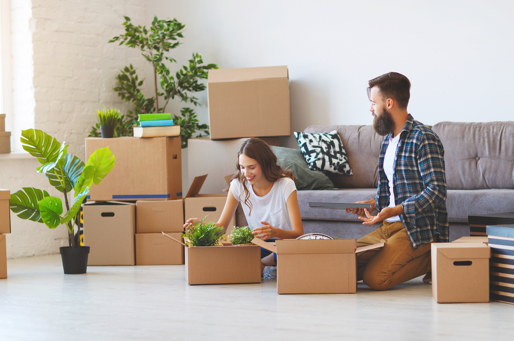 Couple packing items into boxes surrounded by boxes.