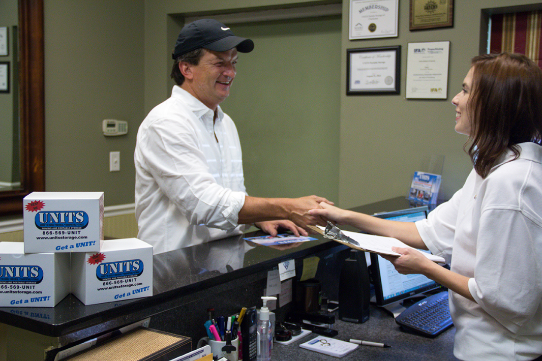 A woman shaking a mans hand with units business card in the back.